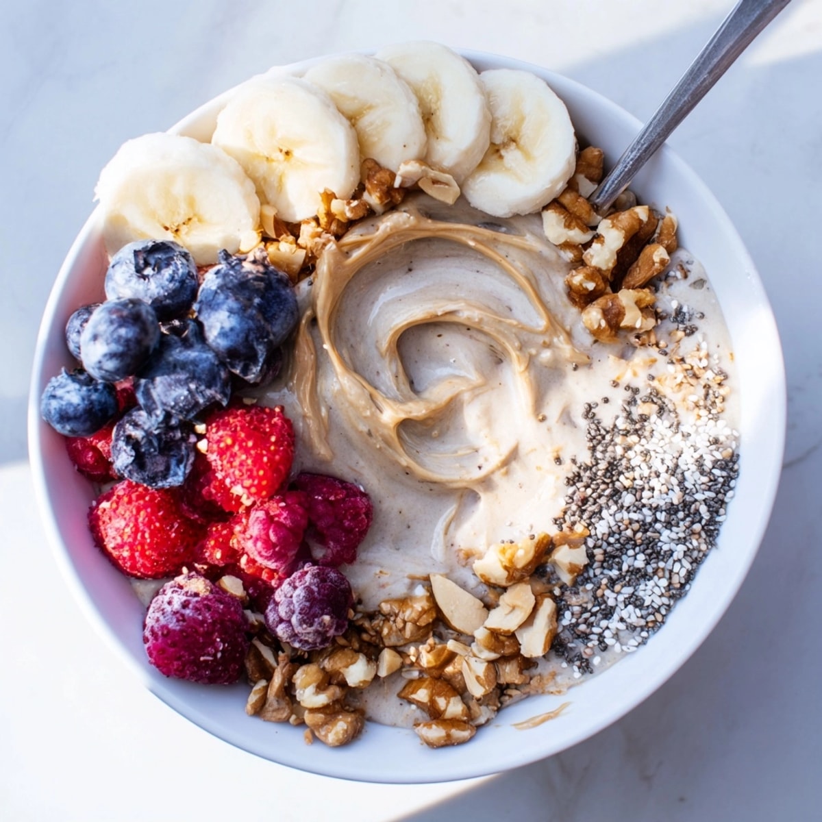 Creamy Protein Peanut Butter Breakfast Bowl, swirled with berries, granola, and sliced banana.