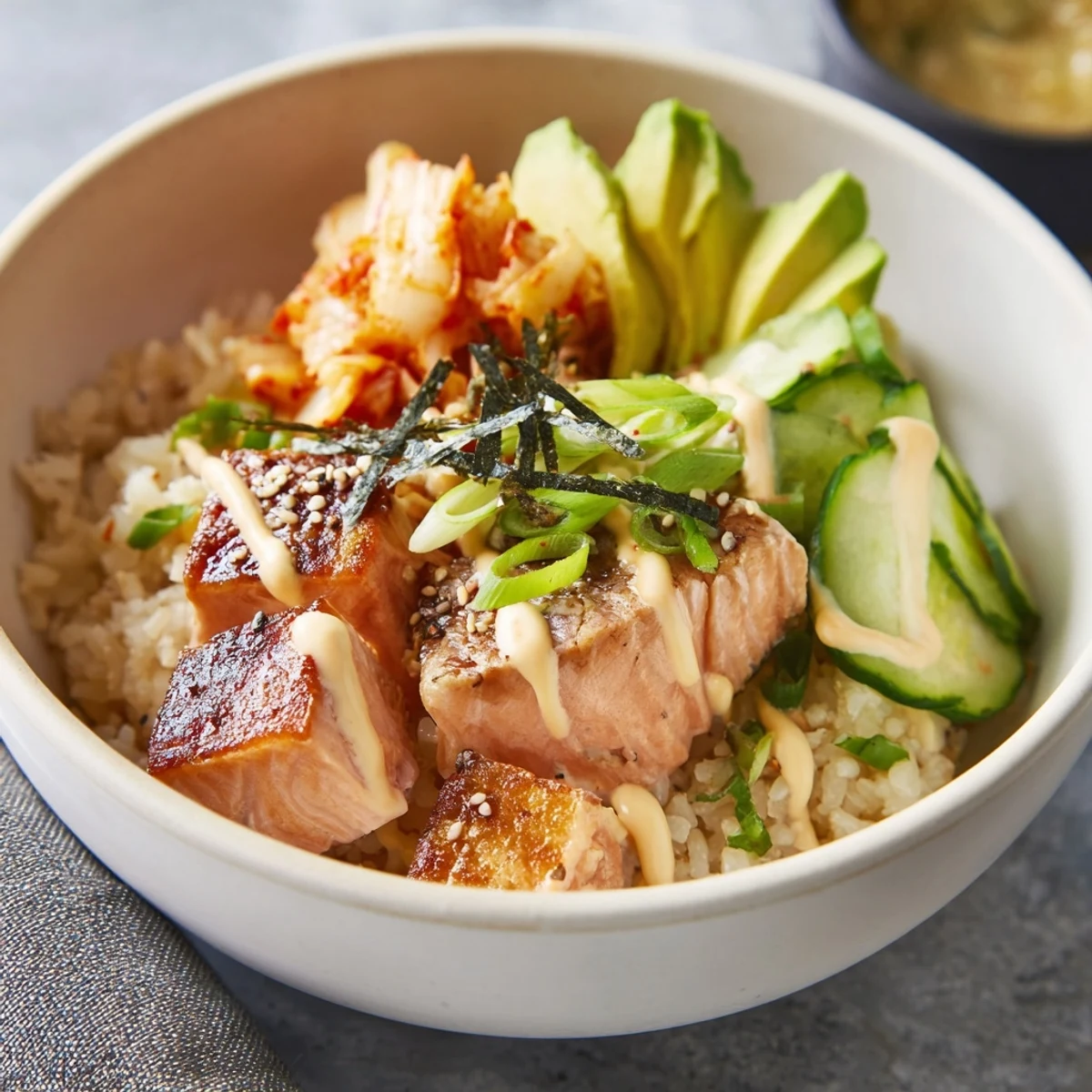 Savory Crispy Salmon Rice Bowl drizzled with creamy spicy mayo and crispy garlic.