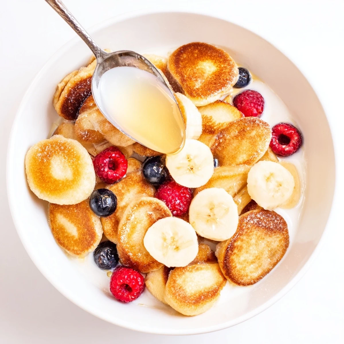 Mini pancake cereal topped with milk and berries for a fun breakfast treat.