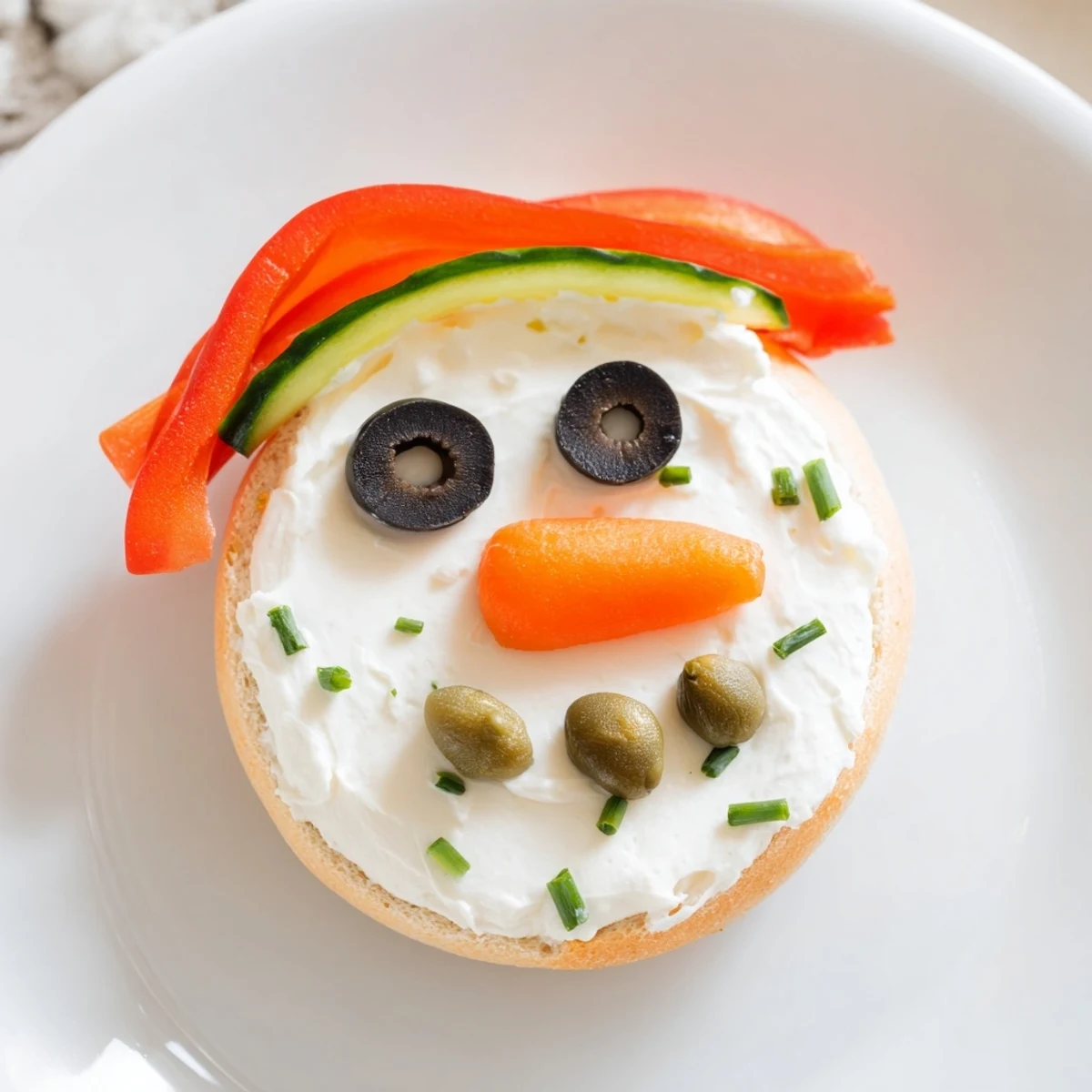Festive snowman mini bagel sandwiches, decorated with colorful veggies and creamy cream cheese.
