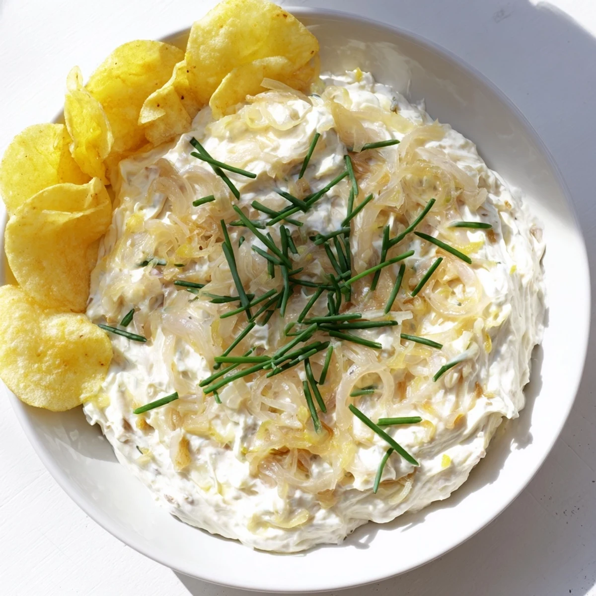 Homemade onion dip served with a generous pile of classic, crunchy and salty potato chips.