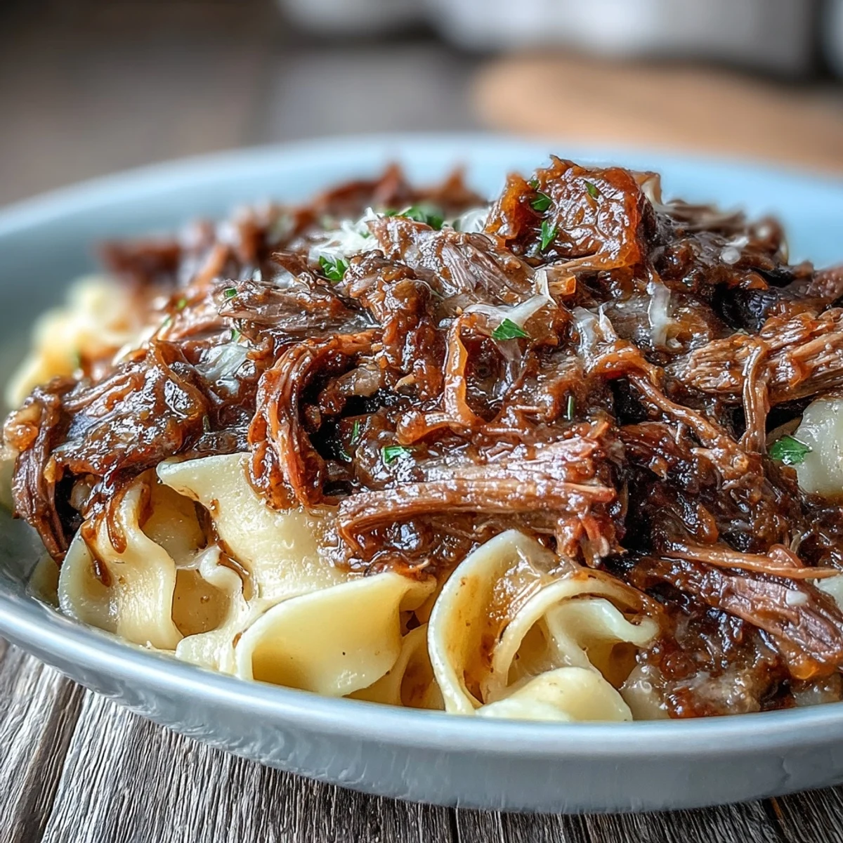 Crockpot French Onion Pot Roast Pasta features tender beef and caramelized onions over buttery egg noodles.