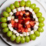 A platter of Summer Watermelon Slice: juicy watermelon with a creamy cheese layer and green olive rind.