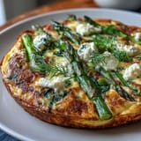 Creamy goat cheese melts over tender asparagus and peas in this colorful spring frittata, ideal for vegetarian breakfast or lunch.