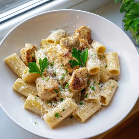 A bowl of creamy garlic Parmesan chicken rigatoni, rich sauce clinging to pasta.  
