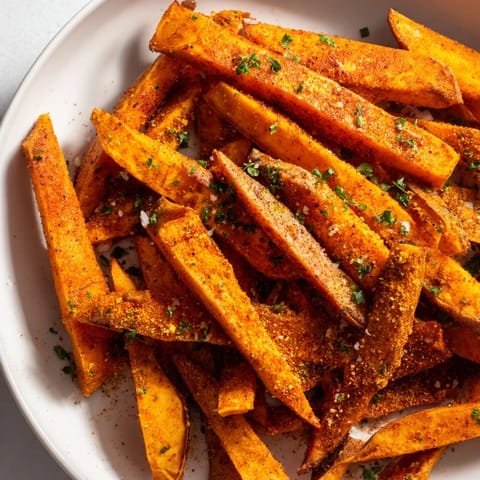 A close-up of vibrantly seasoned Cajun spiced sweet potato fries, offering a spicy, savory aroma.
