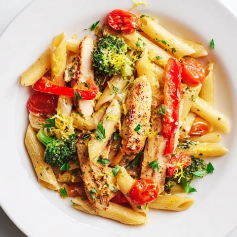 A close-up of Garlic Herb Chicken & Veg Pasta featuring juicy sliced chicken and tender broccoli beside glistening pasta.  