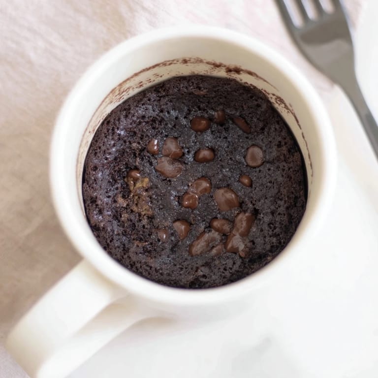 Rich, dark mug cake photographed fresh from the microwave, ready for a delicious, easy dessert.