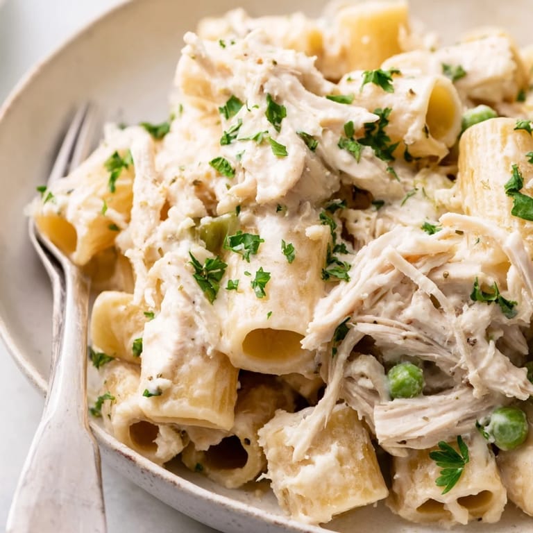 A steamy bowl of Slow Cooker Chicken Alfredo Pasta Bake with pasta glistening in a rich sauce.