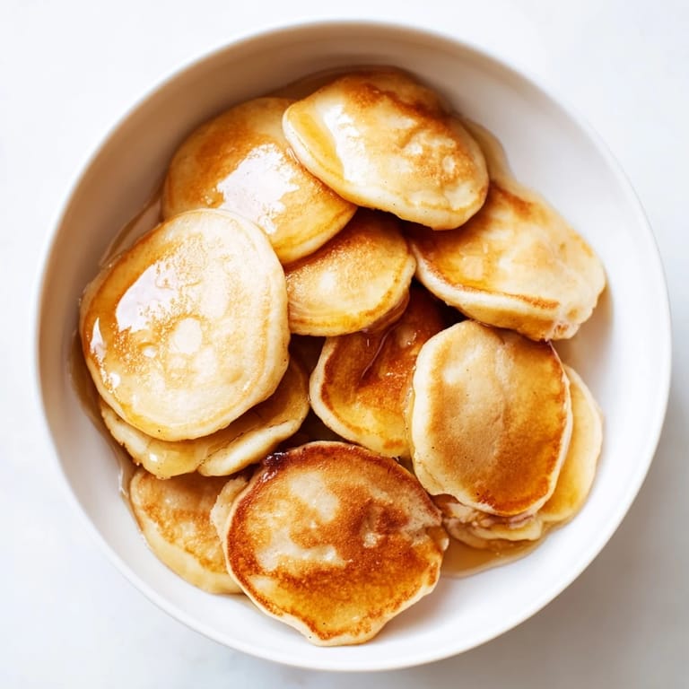 Warm, bite-sized fluffy pancake cereal swimming in milk, a delicious American breakfast treat.