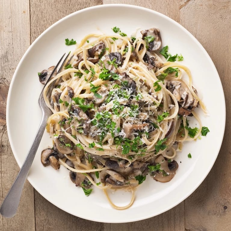 Warm creamy mushroom linguine steaming beside a glass of white wine on a rustic table.