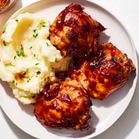 Golden-brown honey BBQ chicken thighs, glistening with sauce, served with perfect garlic mashed potatoes.